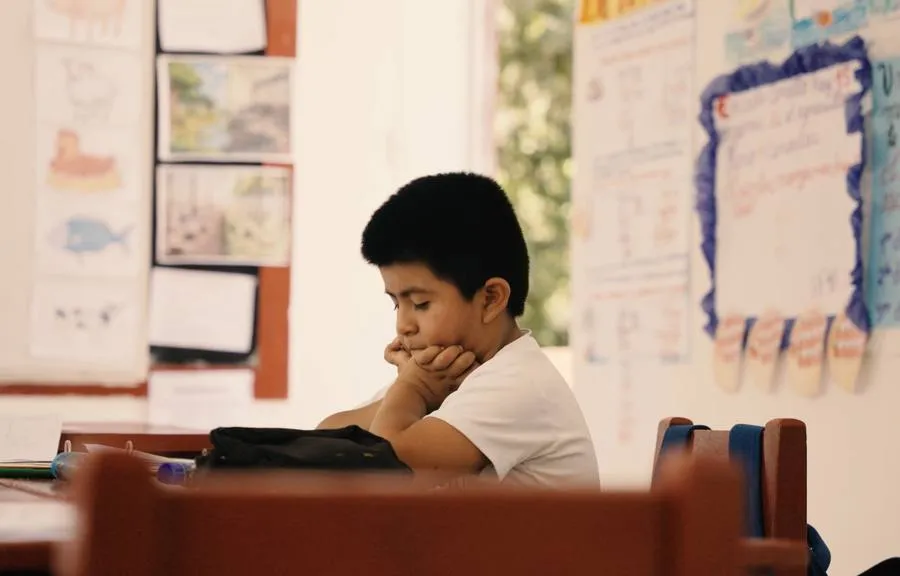 A boy concentrating on his work at his little desk