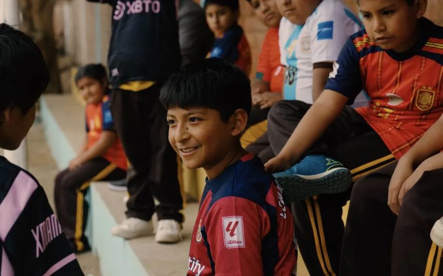 A smiling boy in a football shirt among his classmates